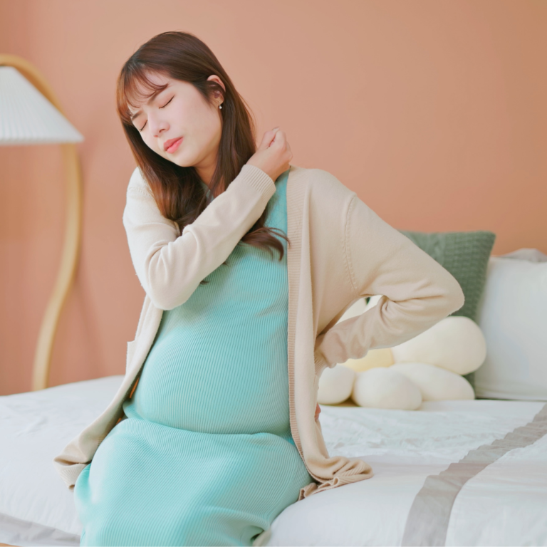 Pregnant woman holding lower back with gentle support, showing chiropractic care benefits during pregnancy in KL